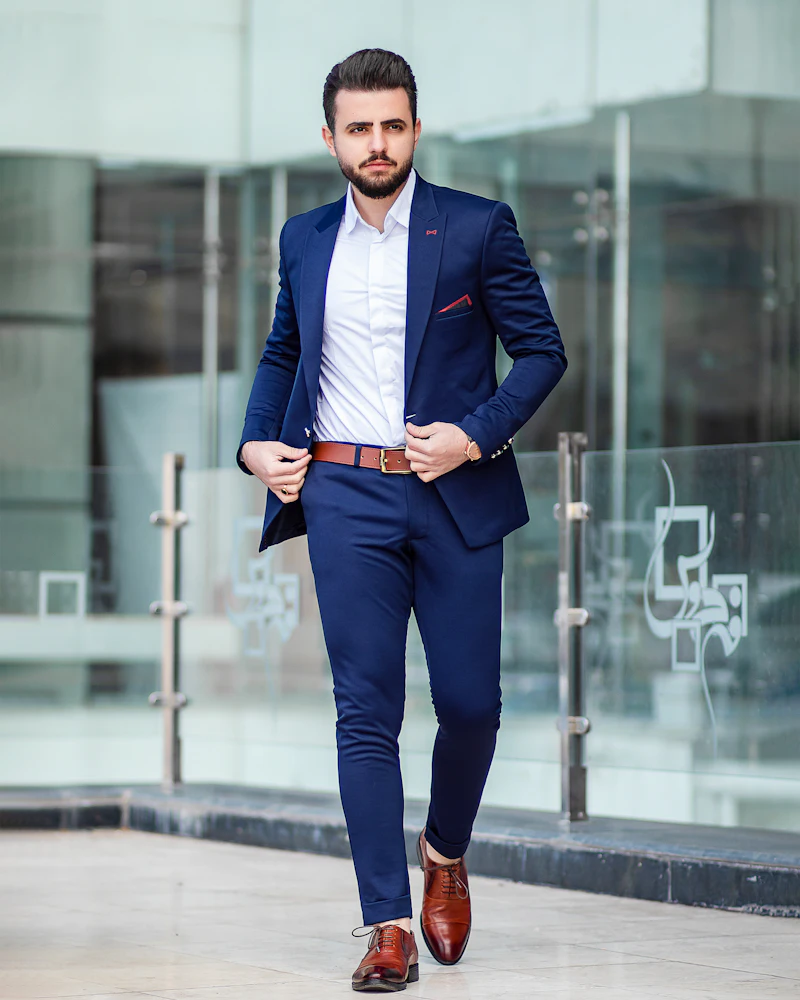 Man in a navy tailored suit walking past glass offices