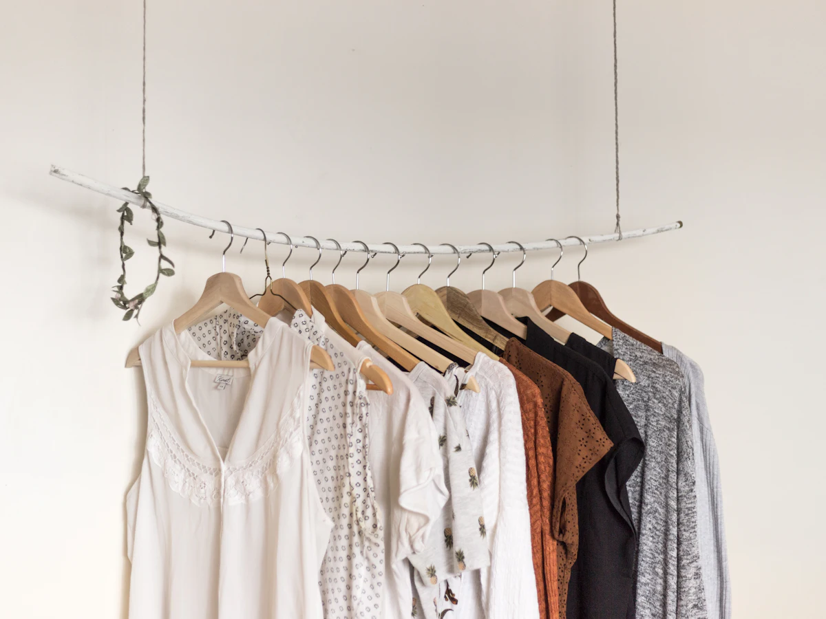 A rail of neutral linen and cotton garments on wooden hangers