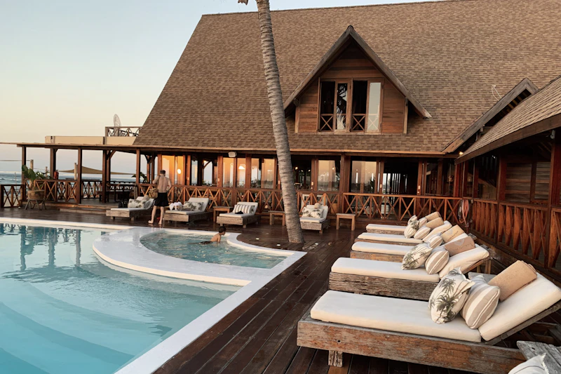 Beach club pool with wooden sun loungers at sunset