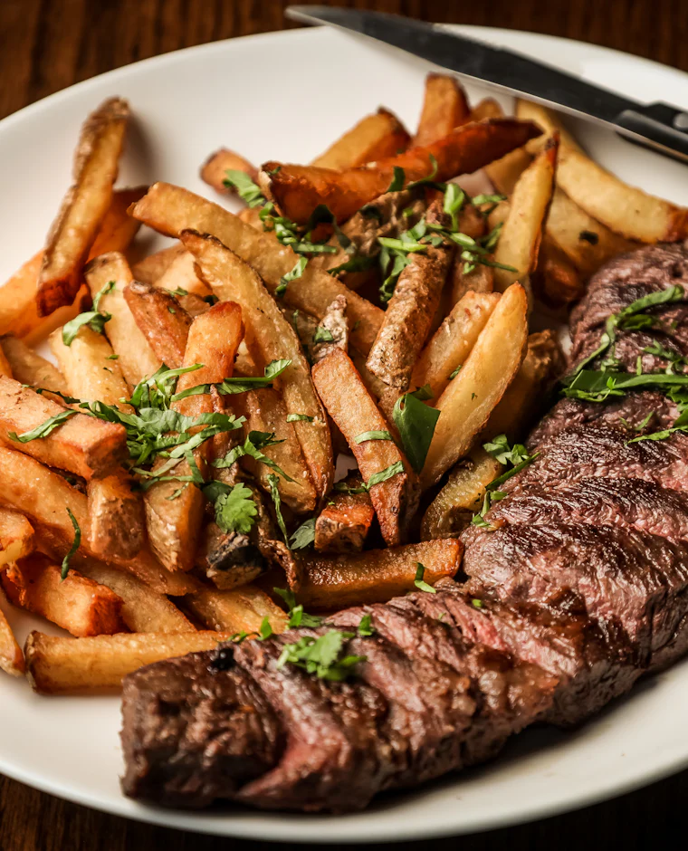 Côte de bœuf sliced beside golden hand-cut frites and fresh herbs