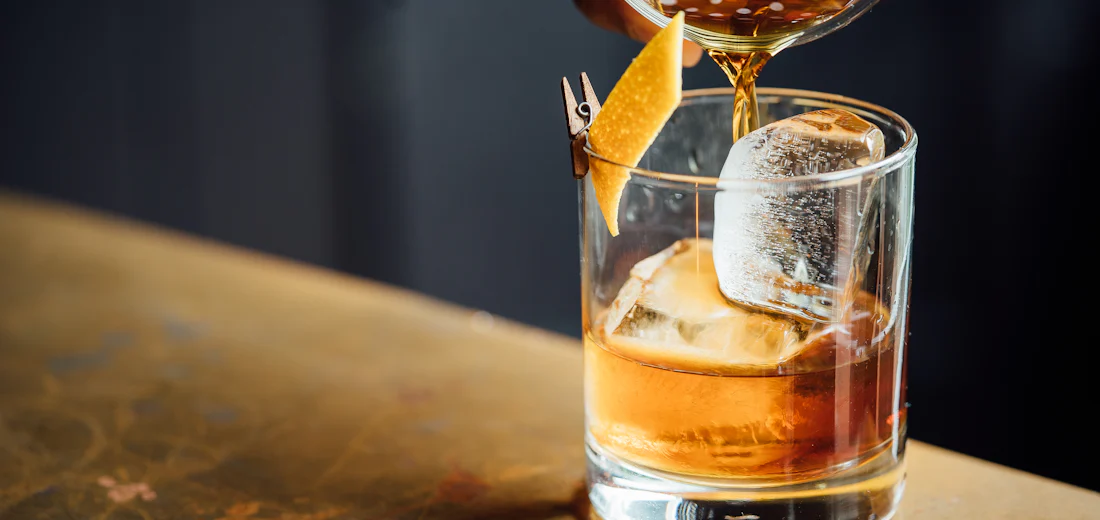 Whisky poured over a crystal-clear ice sphere
