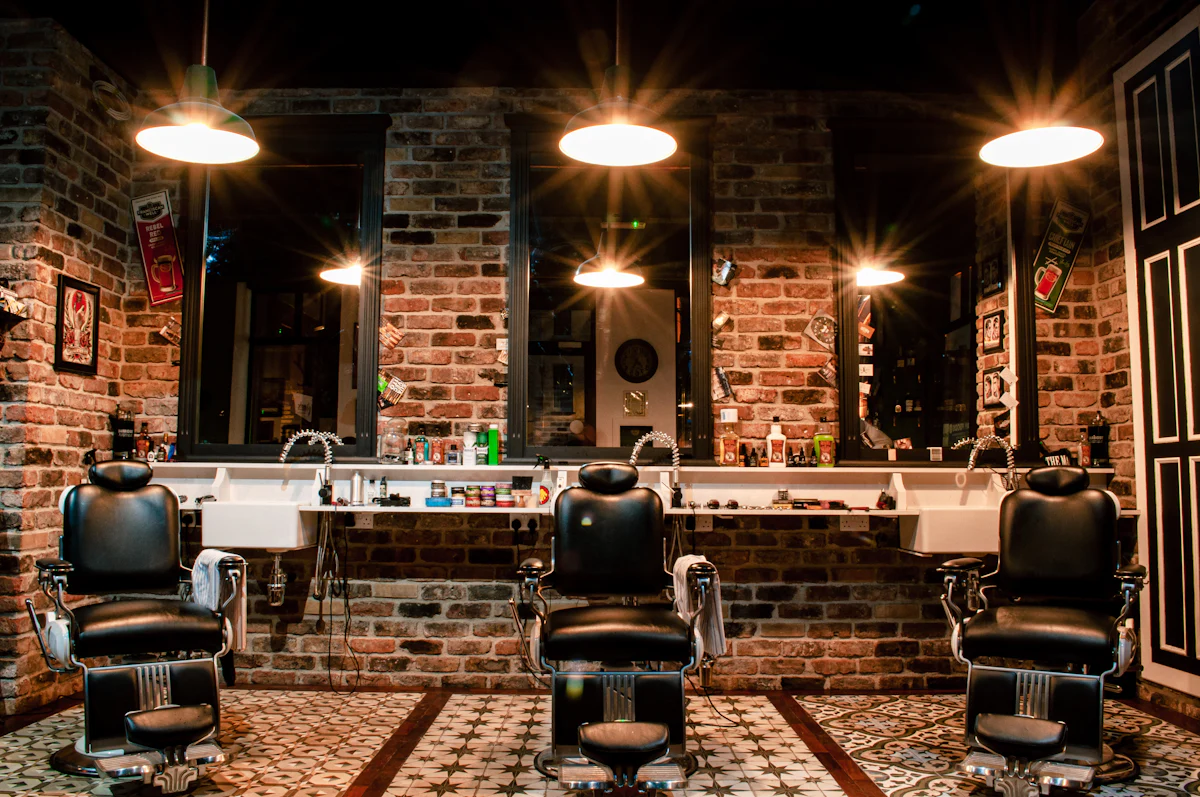 The barber floor at Maison Lina with leather chairs, brick walls and warm pendant lights