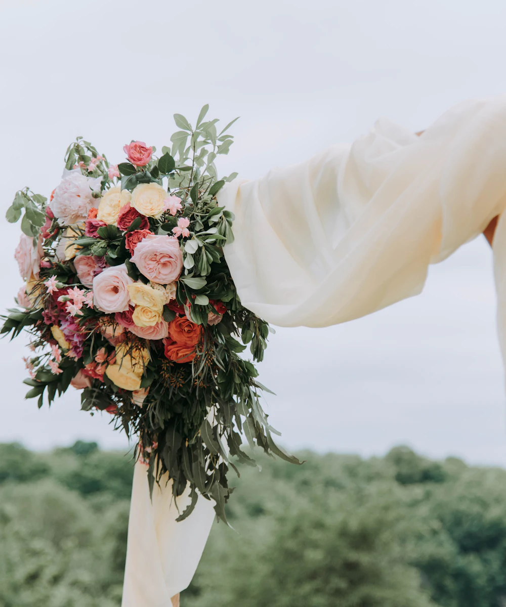 Lush bridal bouquet of peonies and roses against an ivory veil