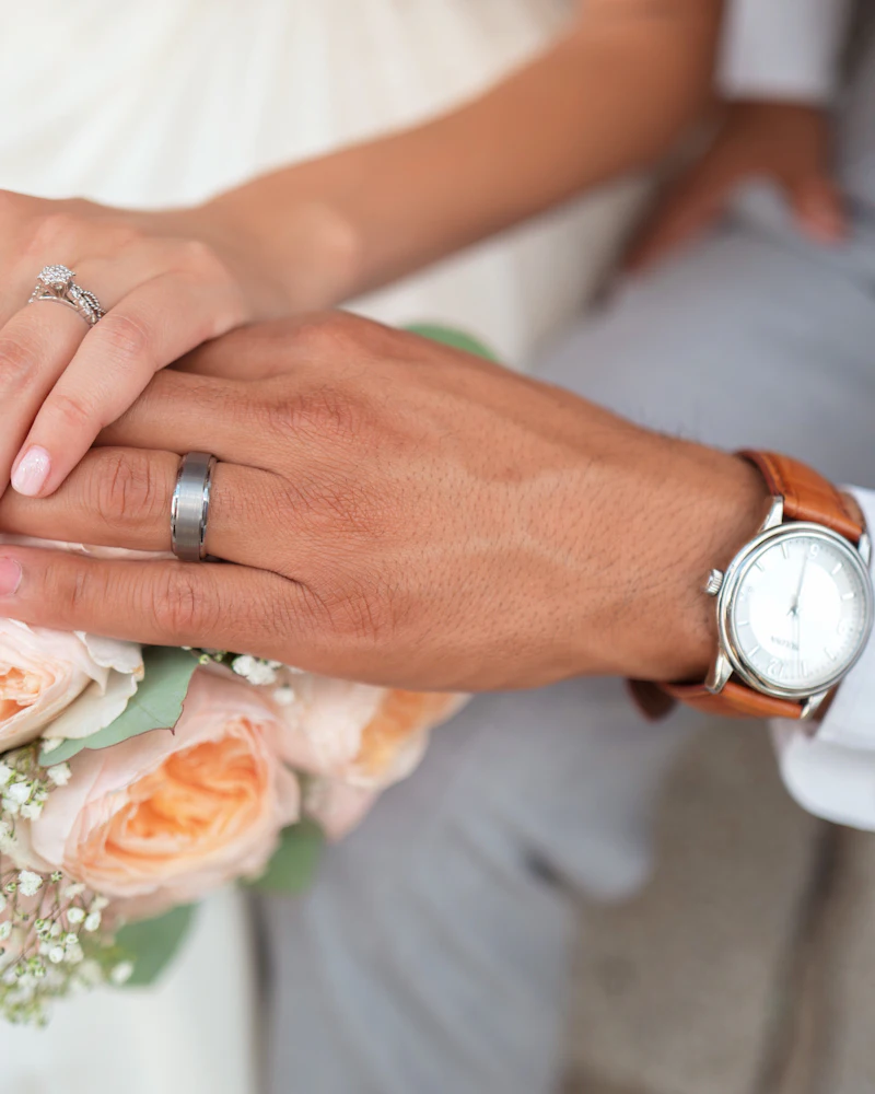 Sarah's hand resting on James's hand, both wearing wedding rings